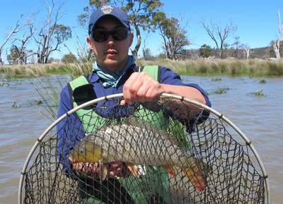 Carp Manahement Program Jonah Yick with one of the four carp, which pushed into a barrier fyke, net this season, in response to warming water temperatures and rising lake levels.