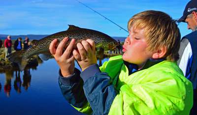 A junior angler at Trout Weekend, very happy with his catch of a fine rainbow trout.