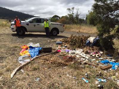 Inland Fisheries Service volunteers Ranald Moore and Jawhar Patil arriving at Green Island on the River Derwent (between Bridgewater and New Norfolk) to begin the clean up with a large amount of rubbish in the foreground